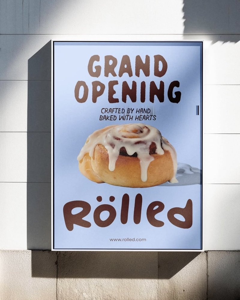 Rölled Grand Opening poster featuring a frosted cinnamon roll, mounted on a storefront